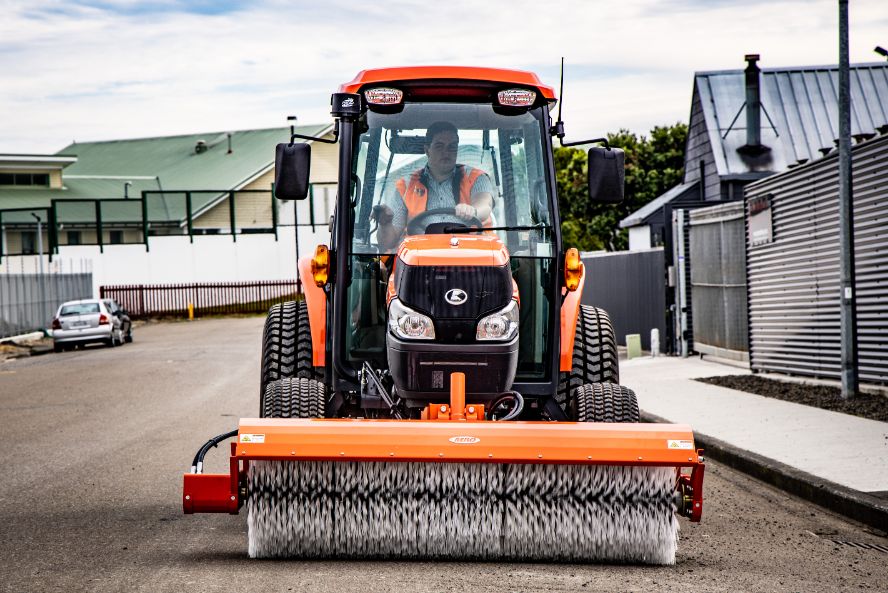 Front view of Orange Neilo Tractor sweeping a street