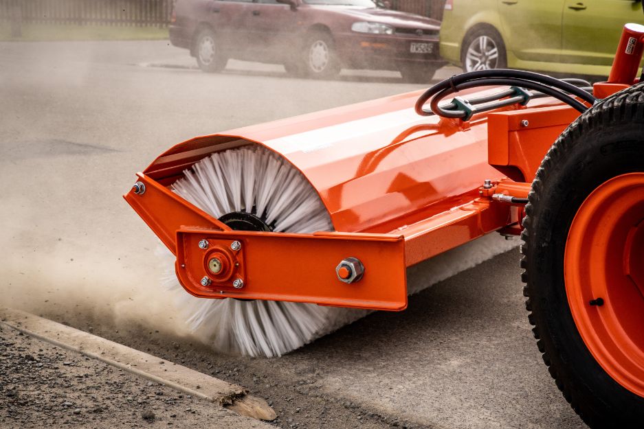 Orange Kubota Road Broom sweeping a street